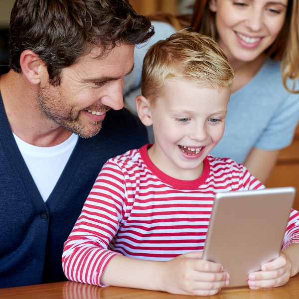 Happy parents and child reading a personalized digital storybook together on a tablet.