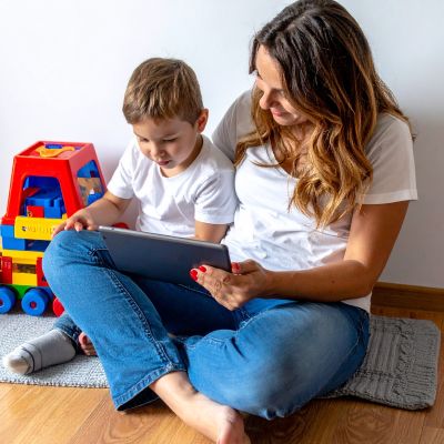 टैबलेट पर व्यक्तिगत डिजिटल कहानी की किताब पढ़ती माँ और बच्चा