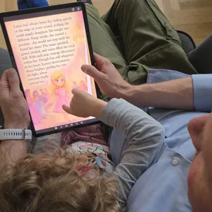 Father and daughter reading a personalized children’s story on a tablet together.